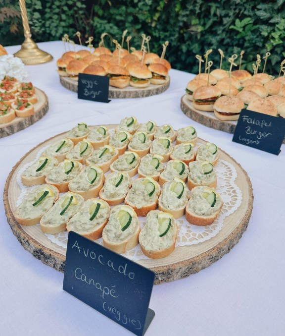 Avocado-Canapés auf einer Holzscheibe, daneben ein Kreidetafel-Schild